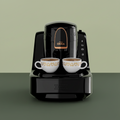 Black coffee machine with two white cups filled with coffee on a white background